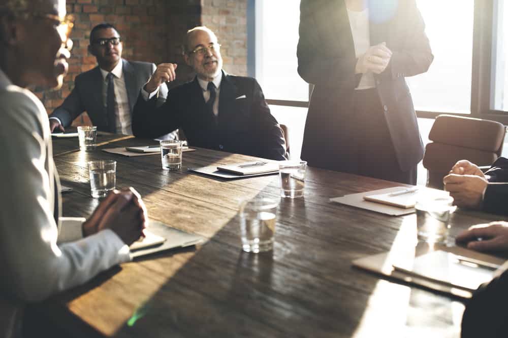 A group of men sit around a conference table.